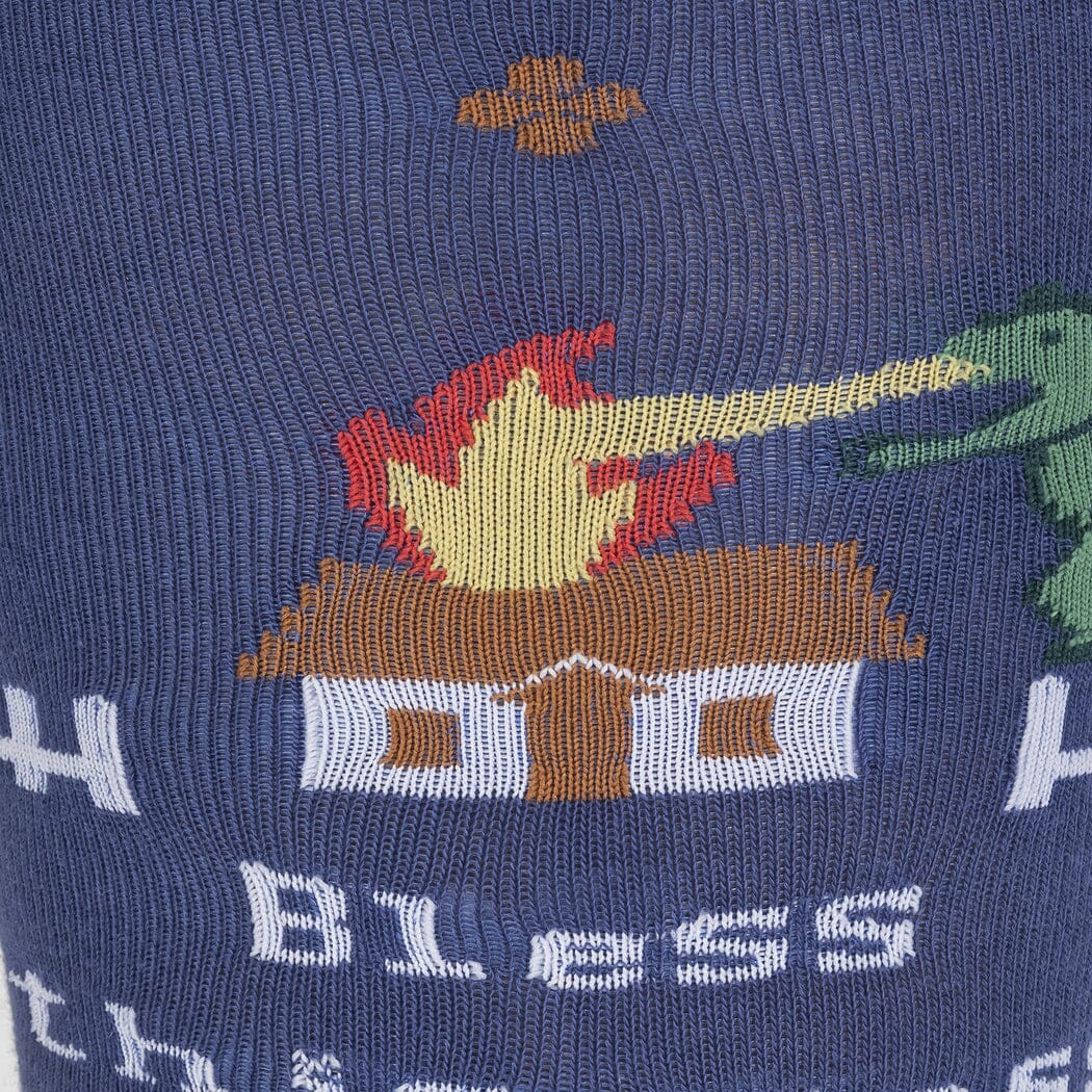 Close-up of the dragon breathing fire onto a burning cottage above the Bless lettering