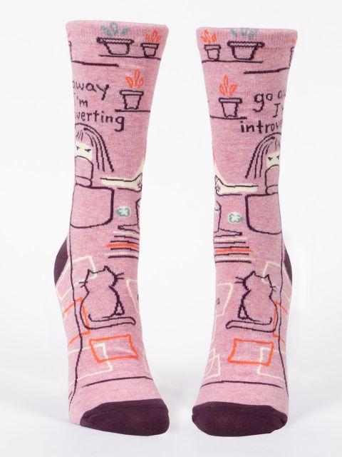 Front-facing view of the pink introverting socks standing upright, showing the cozy room doodles and cat across both socks