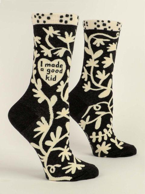 Women's black crew socks shown at an angle with cream folk-art vines and flowers and 'I made a good kid' in a heart