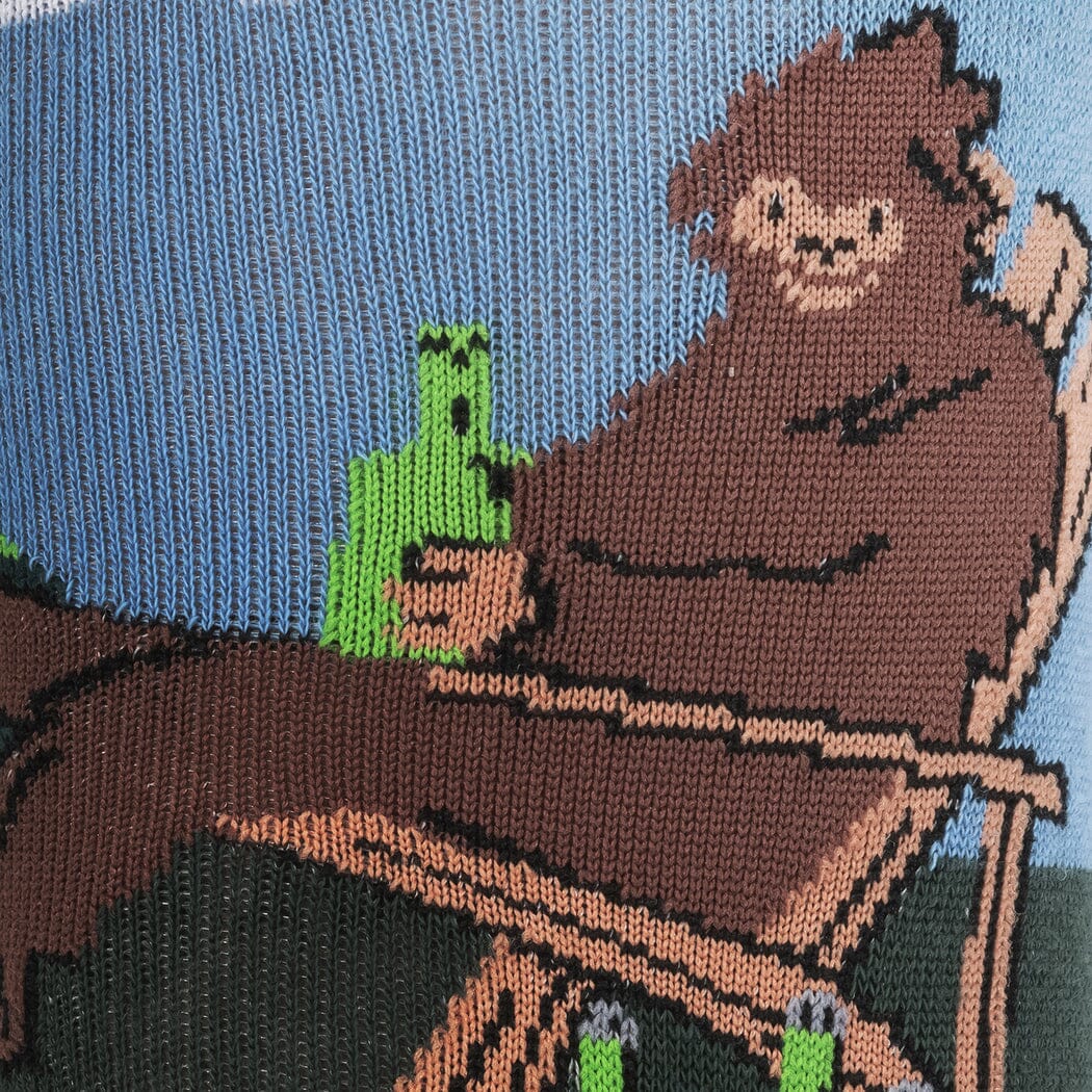 Close-up of Bigfoot lounging in a chair holding a green bottle with a bucket of drinks nearby
