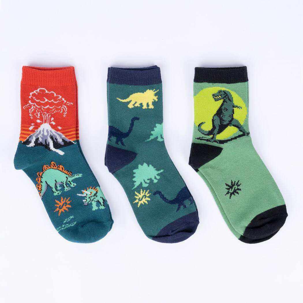 Three kids' dinosaur crew socks laid flat: orange volcano pair, green dinosaur-print pair, and a green T-rex pair