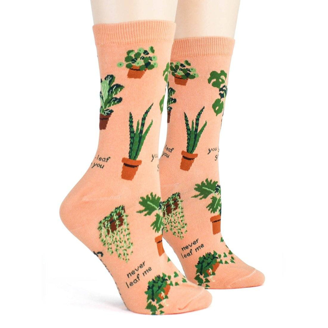 Front view of the plant socks worn on legs, showing aloe and snake plants on the peach knit