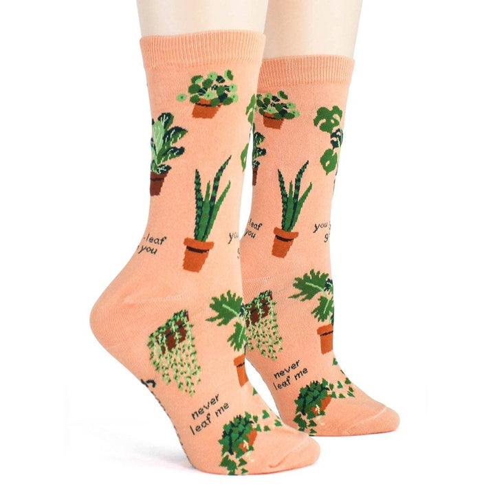 Front view of the plant socks worn on legs, showing aloe and snake plants on the peach knit