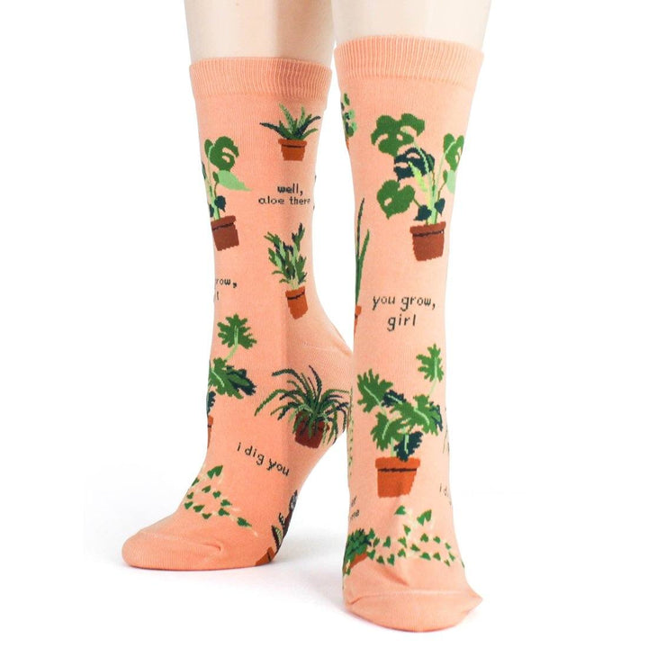 Three-quarter worn view of the plant socks featuring "you grow, girl" and a potted spider plant