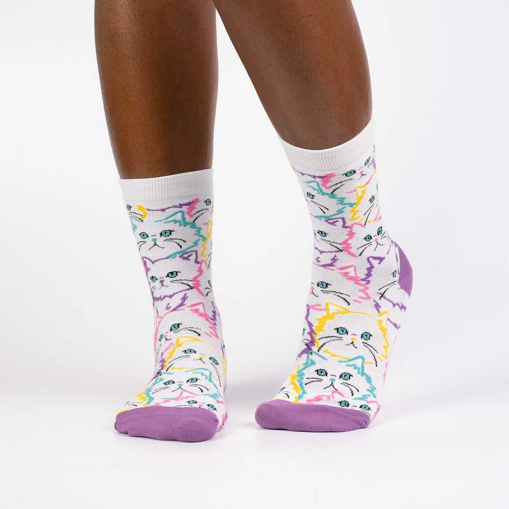 Person wearing white crew socks covered in neon-outlined fluffy cats, front view