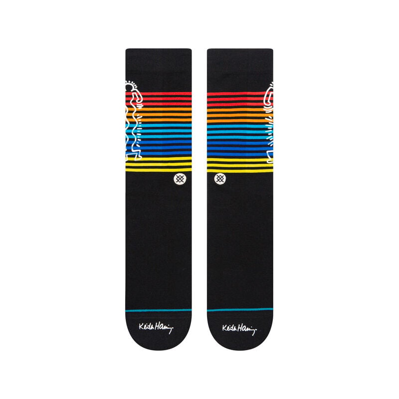 Flat front view of black Keith Haring crew socks showing rainbow stripes and signature on the foot