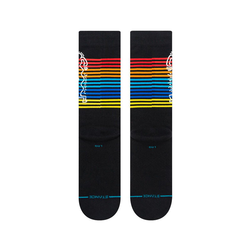 Angled view of black Keith Haring crew socks with rainbow stripes and the line-art figure