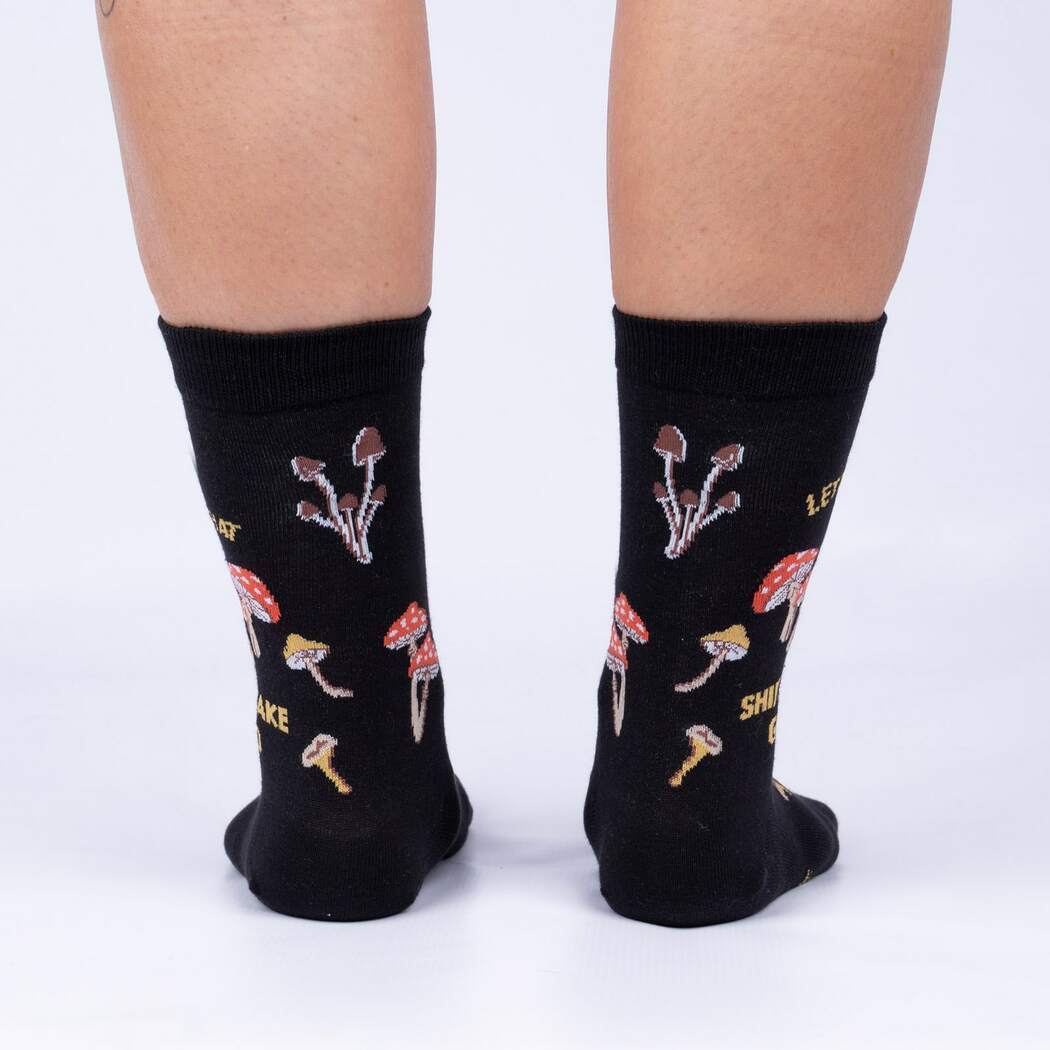 Back view of model wearing the Let That Shiitake Go crew socks showing the mushroom pattern around the heel