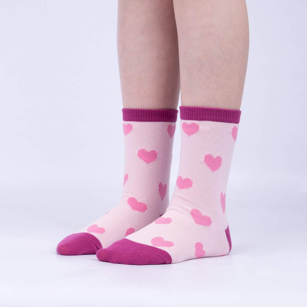 Child wearing the pale pink heart junior crew socks with berry cuff, side view