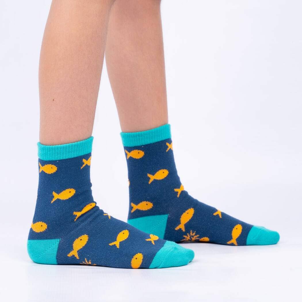 Child wearing the navy fish socks with orange fish and teal heel and toe