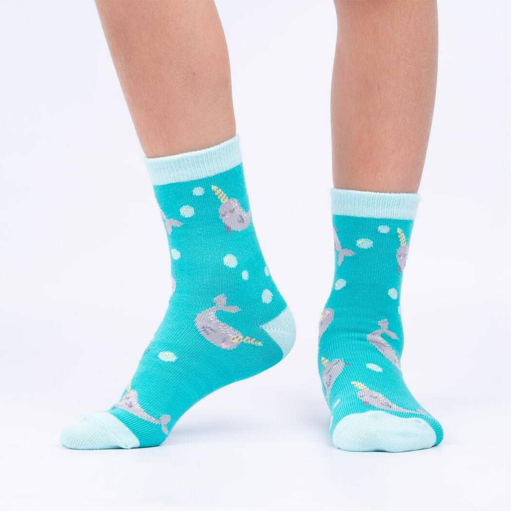 Child wearing the teal narwhal socks with sparkly purple narwhals and bubbles