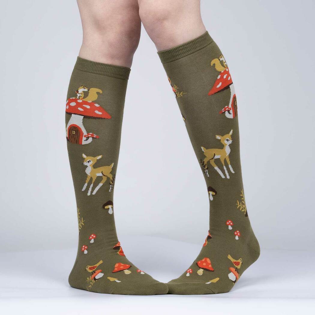 Person wearing olive green woodland knee high socks with mushroom house, fawn and birds, front view