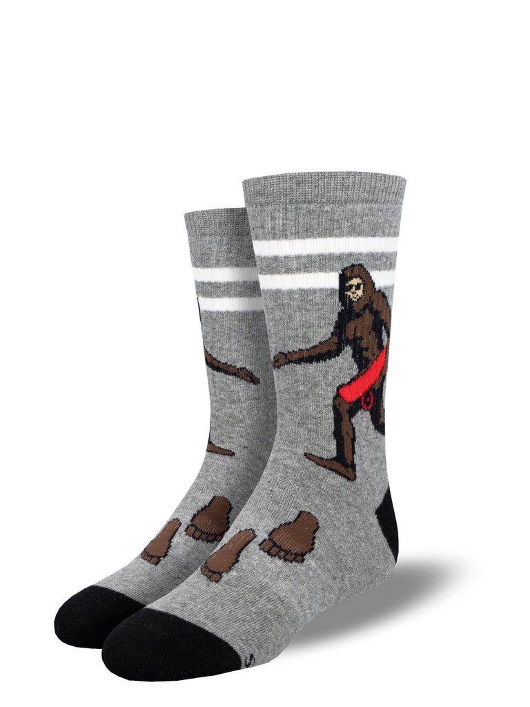 Pair of kids' heathered gray athletic crew socks with a skateboarding brown Bigfoot, footprints, and white stripes