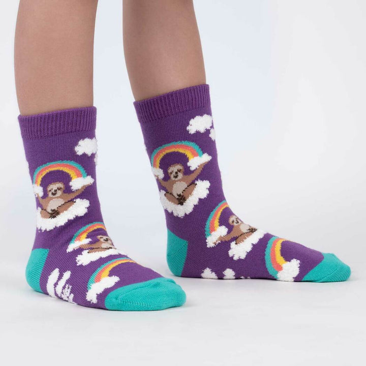 Side view of child wearing the purple fuzzy sloth-and-rainbow crew socks