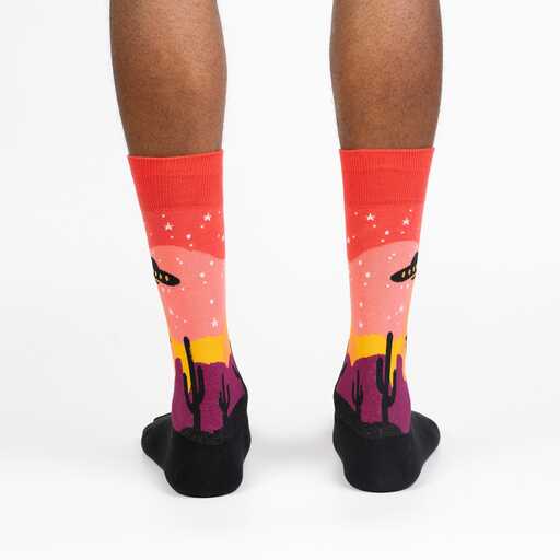 Back view of the Area 51 socks worn on legs, showing the sunset sky, stars, and cactus horizon