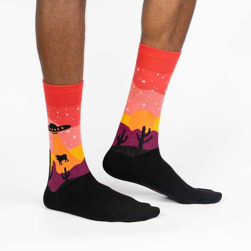 Side view of the Area 51 socks worn on legs, showing the UFO, cow, and cactus desert scene
