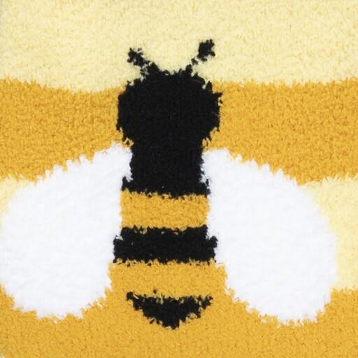Close-up of a single fuzzy bumblebee with white wings knit into the gold striped slipper sock