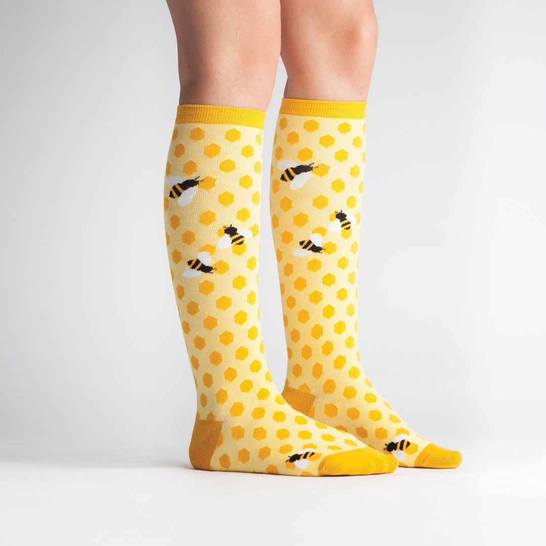 Model wearing yellow honeycomb bee knee high socks, side view