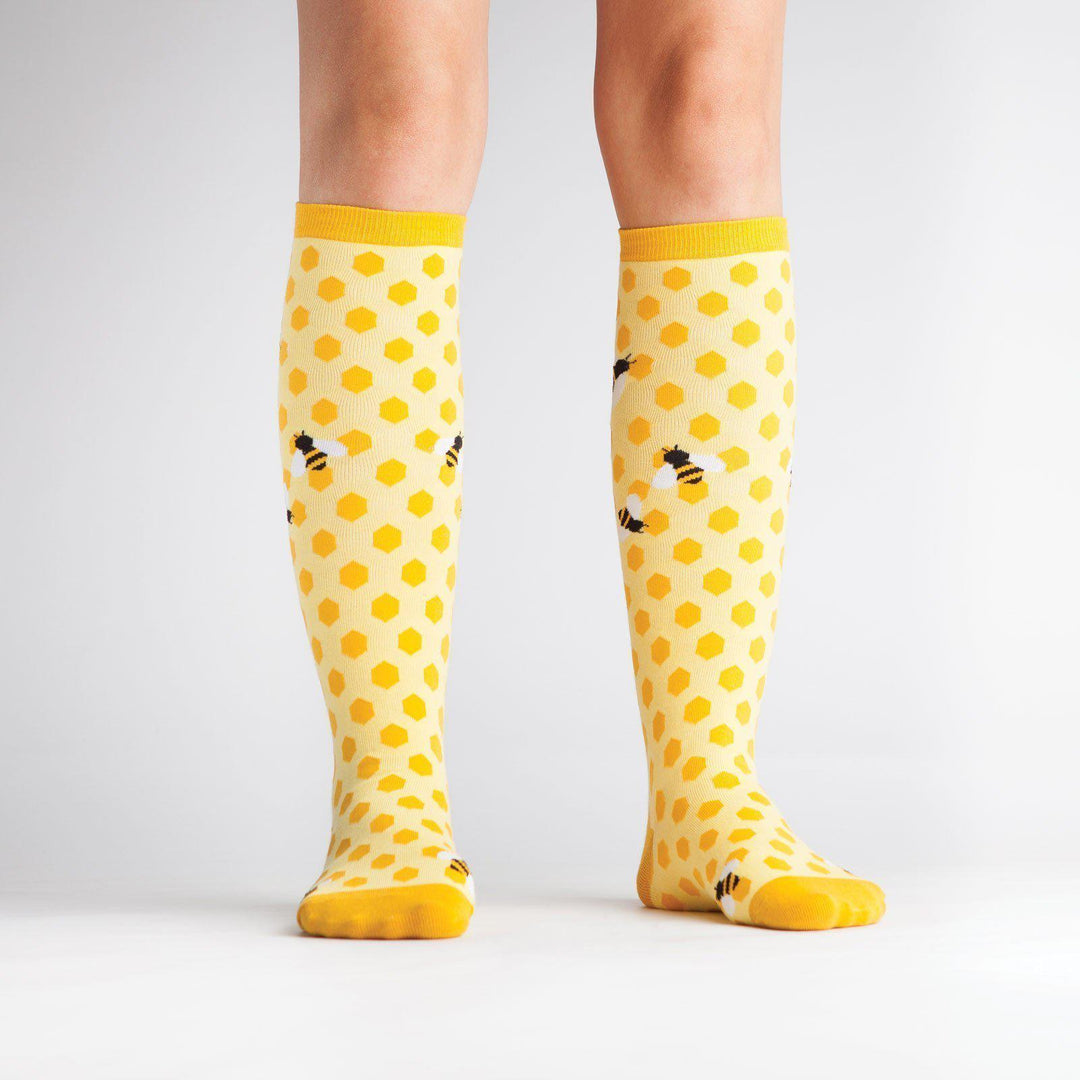 Model wearing yellow honeycomb bee knee high socks, front view