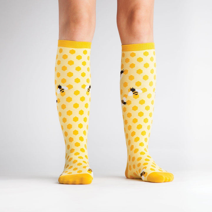 Model wearing yellow honeycomb bee knee high socks, front view