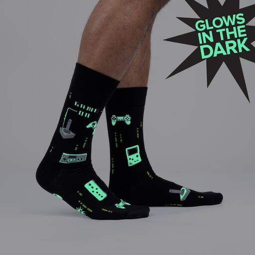 Black gaming crew socks shown glowing green in the dark on legs, marked Glows in the Dark