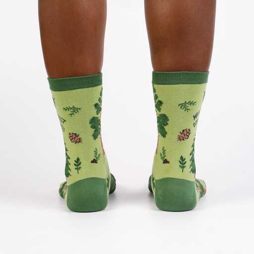 Back view of the green forest socks worn, showing trees, leaves and pinecones with dark green heels
