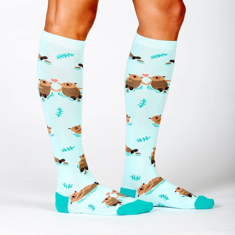 Pair of mint otter knee high socks worn, showing otters and heart pattern