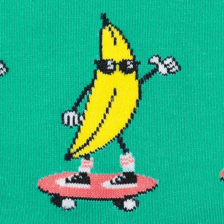 Close-up of a cartoon banana in sunglasses riding a pink skateboard on a green sock