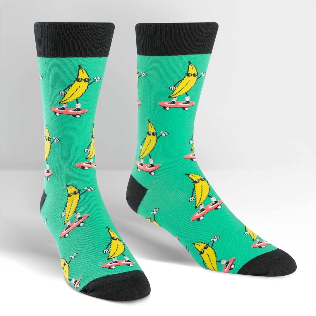 Pair of green crew socks covered in skateboarding bananas wearing sunglasses, black cuff heel and toe
