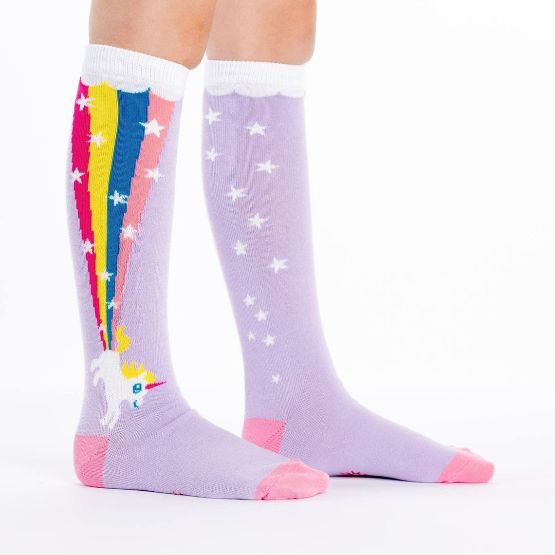 Lavender kids' knee high socks worn, one showing a unicorn blasting a rainbow up the leg
