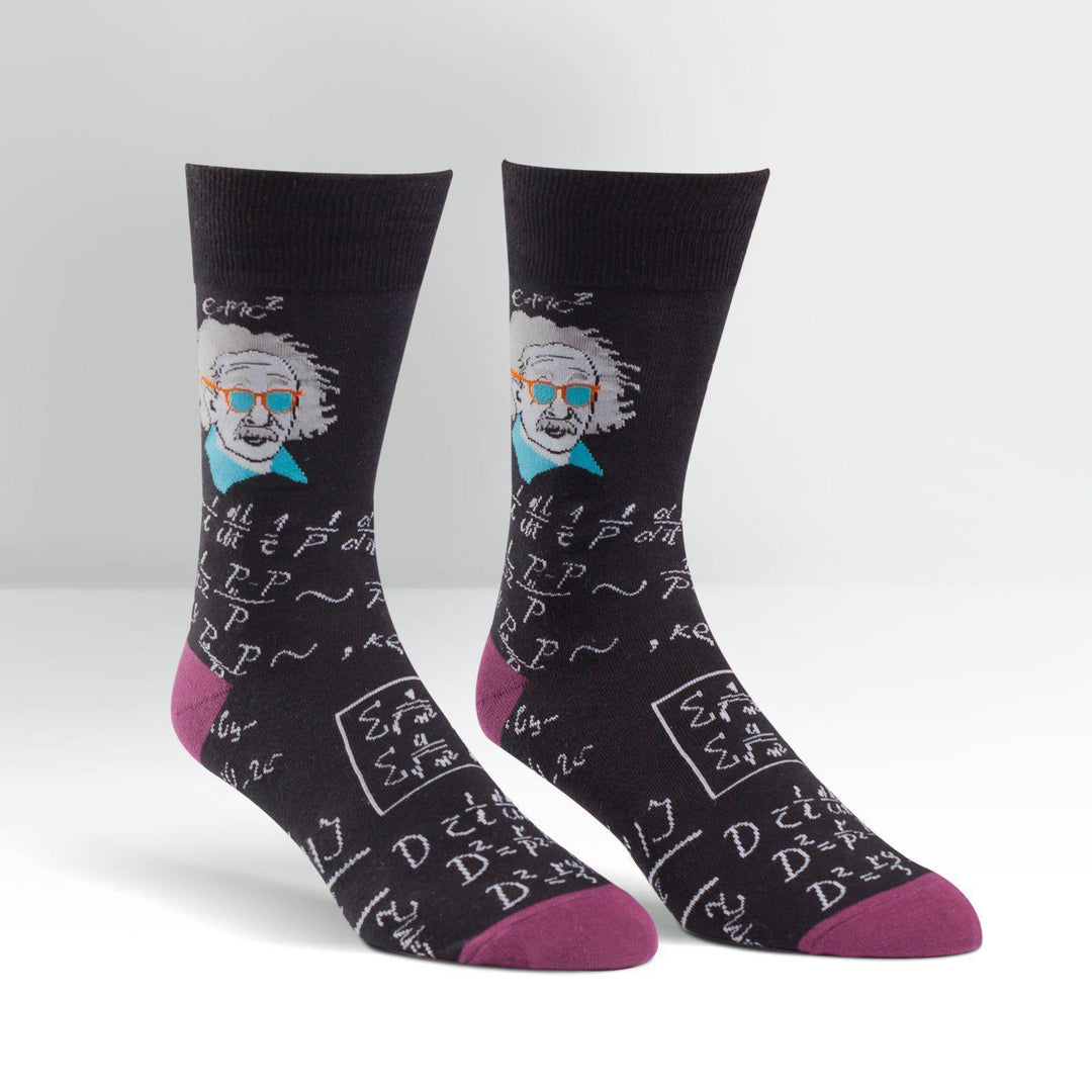 Pair of men's black Einstein crew socks shown flat, featuring Einstein in orange sunglasses, scribbled equations, and E=mc2; magenta heel and toe.