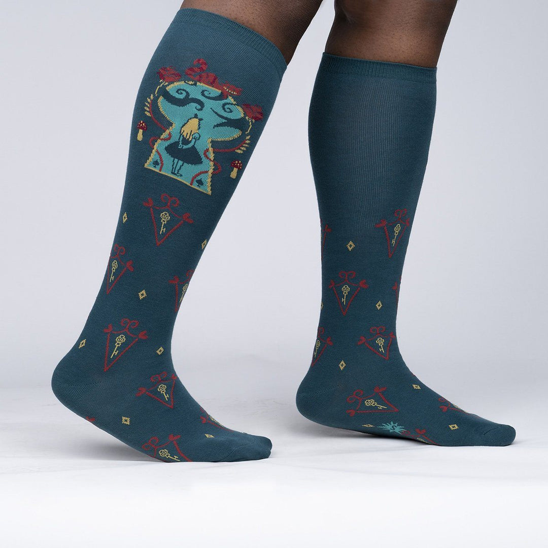 Side view of the Alice knee-highs worn on legs, showing the framed Alice panel and key-and-diamond pattern