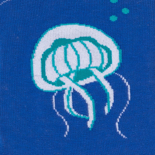 Close-up of a single white-and-teal knit jellyfish with trailing tentacles on deep blue