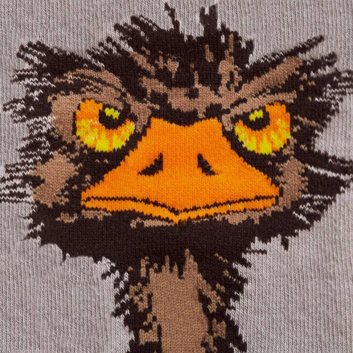 Close-up of the scruffy ostrich face with yellow eyes and orange beak on a gray sock