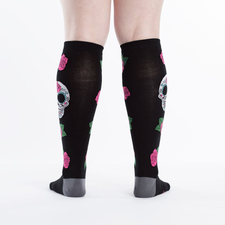 Back view of black sugar skull knee high socks worn on a person&