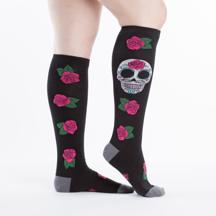 Side view of black sugar skull knee high socks worn on a person&