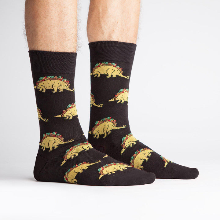 Black crew socks with taco-dinosaurs worn on a model&