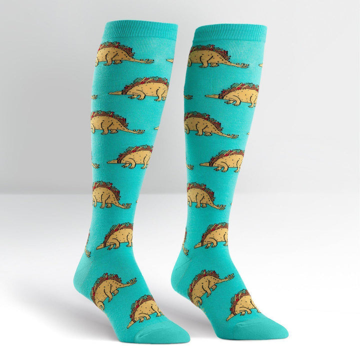 Pair of turquoise knee high socks covered in dinosaurs with taco shells for backs