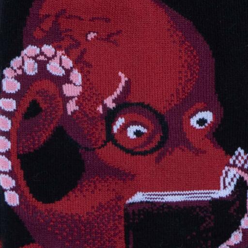 Close-up of a red octopus in round glasses reading a book, knit on a black sock