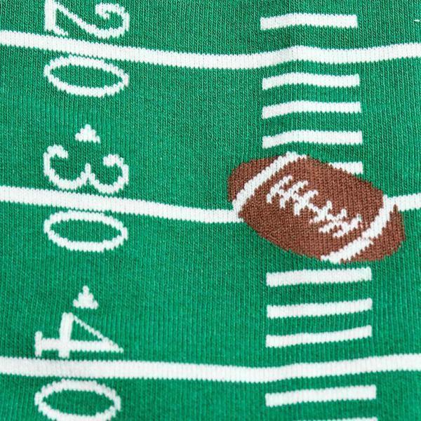 Close-up of football field sock with yard markers and a football