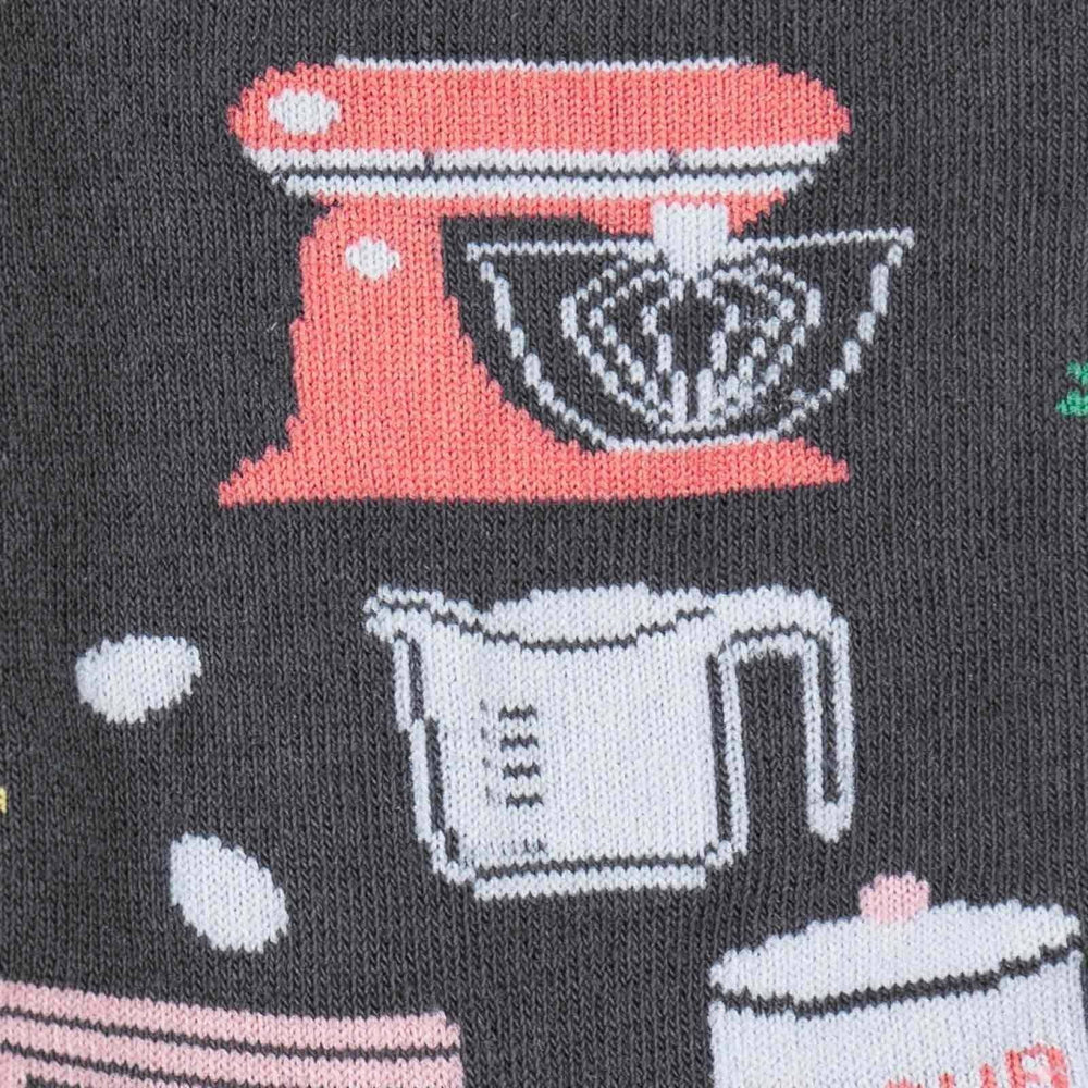 Close-up of a coral stand mixer and measuring cup baked into a gray sock