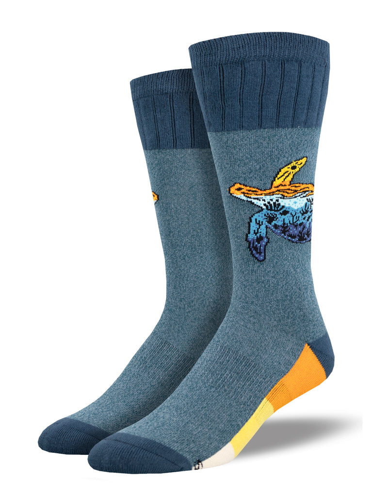 Pair of heather blue men's boot socks displayed upright, with a ribbed cuff and a sea turtle whose shell holds a mountain sunset scene