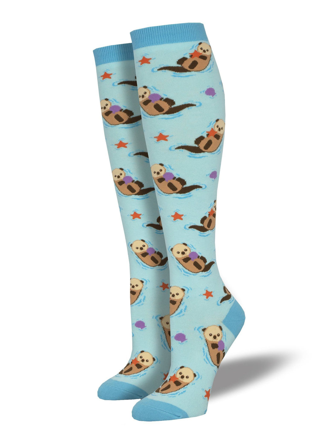 Women's sea otter knee-high socks on leg forms, sky blue with floating otters, shells, and orange starfish