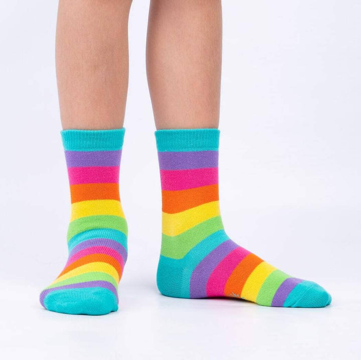 Child wearing the bright rainbow-striped crew socks with teal cuffs