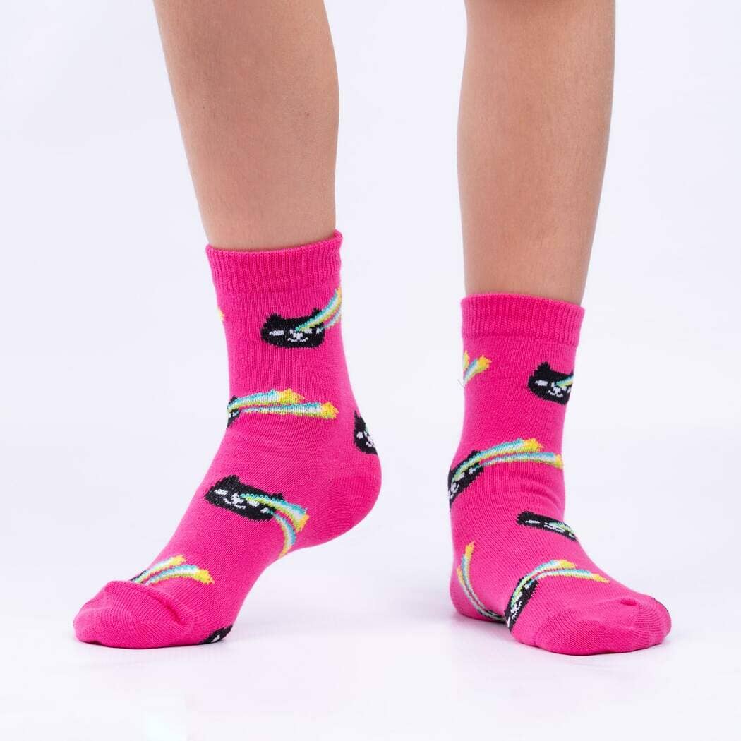 Child wearing the hot-pink socks with black cats trailing rainbow comet tails