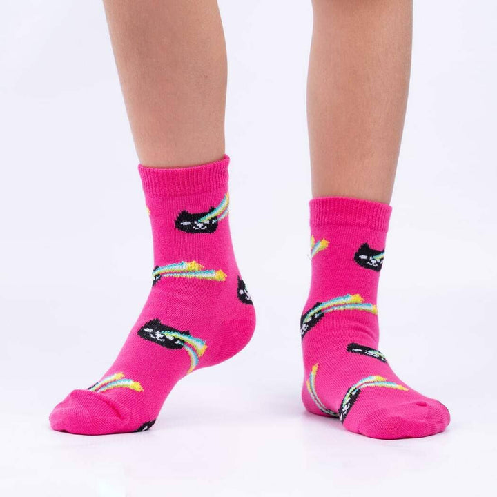 Child wearing the hot-pink socks with black cats trailing rainbow comet tails