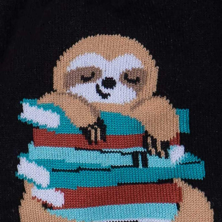 Close-up of the sleepy sloth hugging a stack of striped books