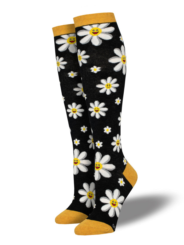 Pair of women's black knee high socks with white daisies with yellow smiley-face centers and golden cuffs, heels, and toes