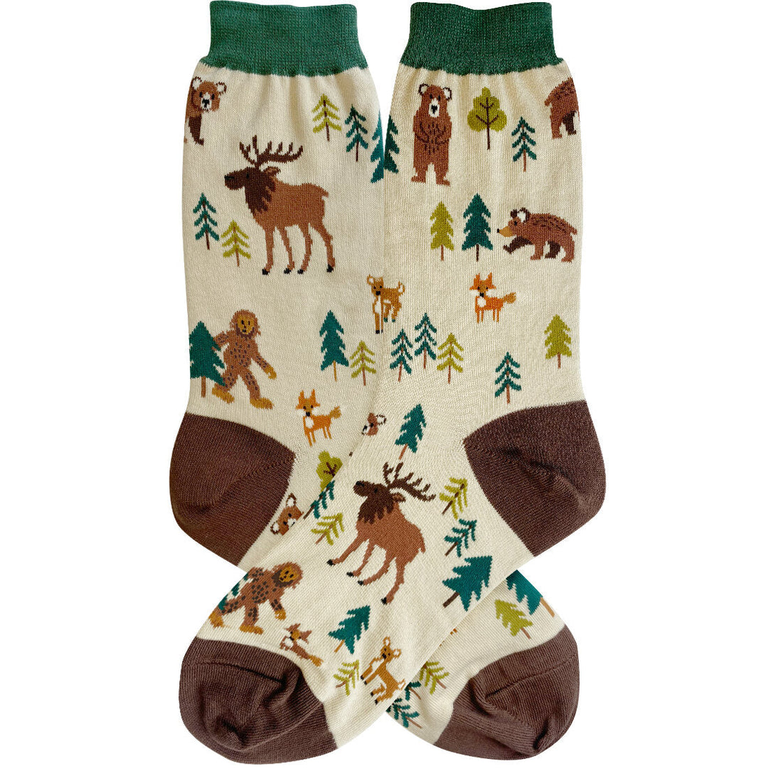 Cream women's crew socks with green cuff and brown heel, patterned with bears, moose, foxes, deer, evergreens, and a walking Bigfoot