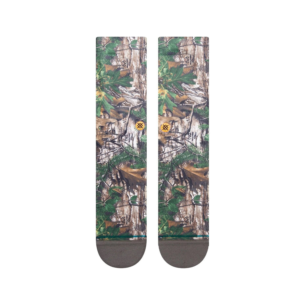 Top-down view of camo crew socks showing detailed forest leaf-and-branch print and small orange logo